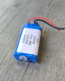 Blue battery with wires on a wooden surface